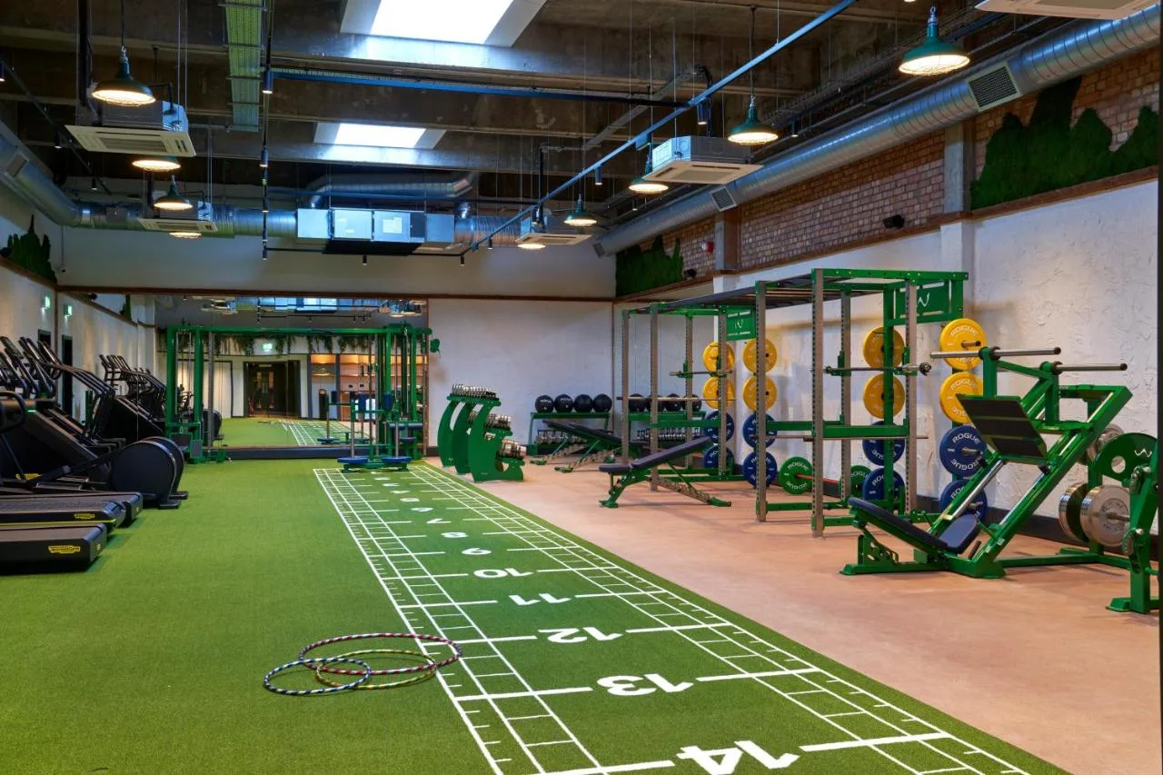 Gym with green carpeted floor and machines at Treehouse Hotel Manchester